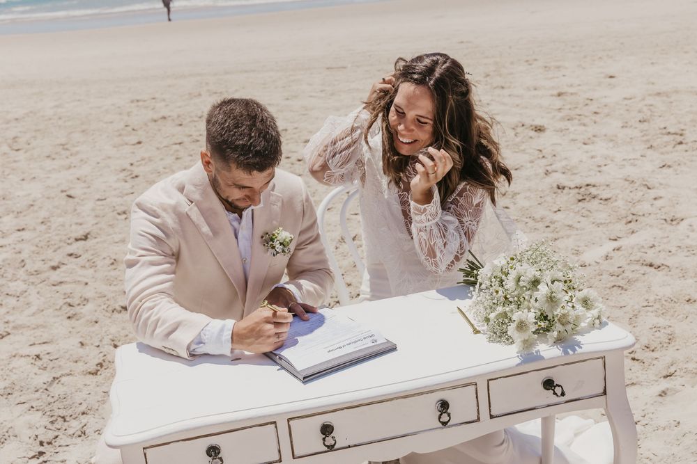 Bride and groom signing their marriage certificate on the beach after their intimate Byron Bay wedding ceremony.
