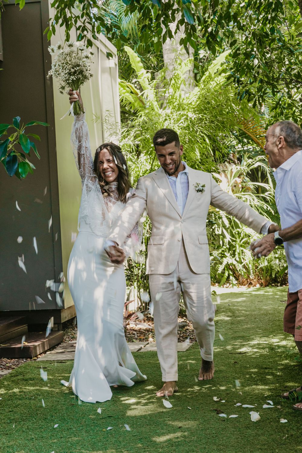 Bride and groom walking back down the aisle after their Byron Bay wedding ceremony, surrounded by family, laughter and celebration.