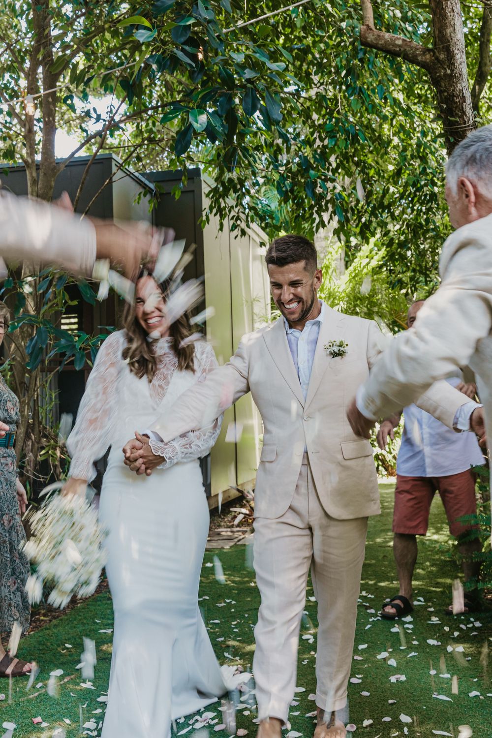 Bride and groom walking back down the aisle after their Byron Bay wedding ceremony, surrounded by family, laughter and celebration.