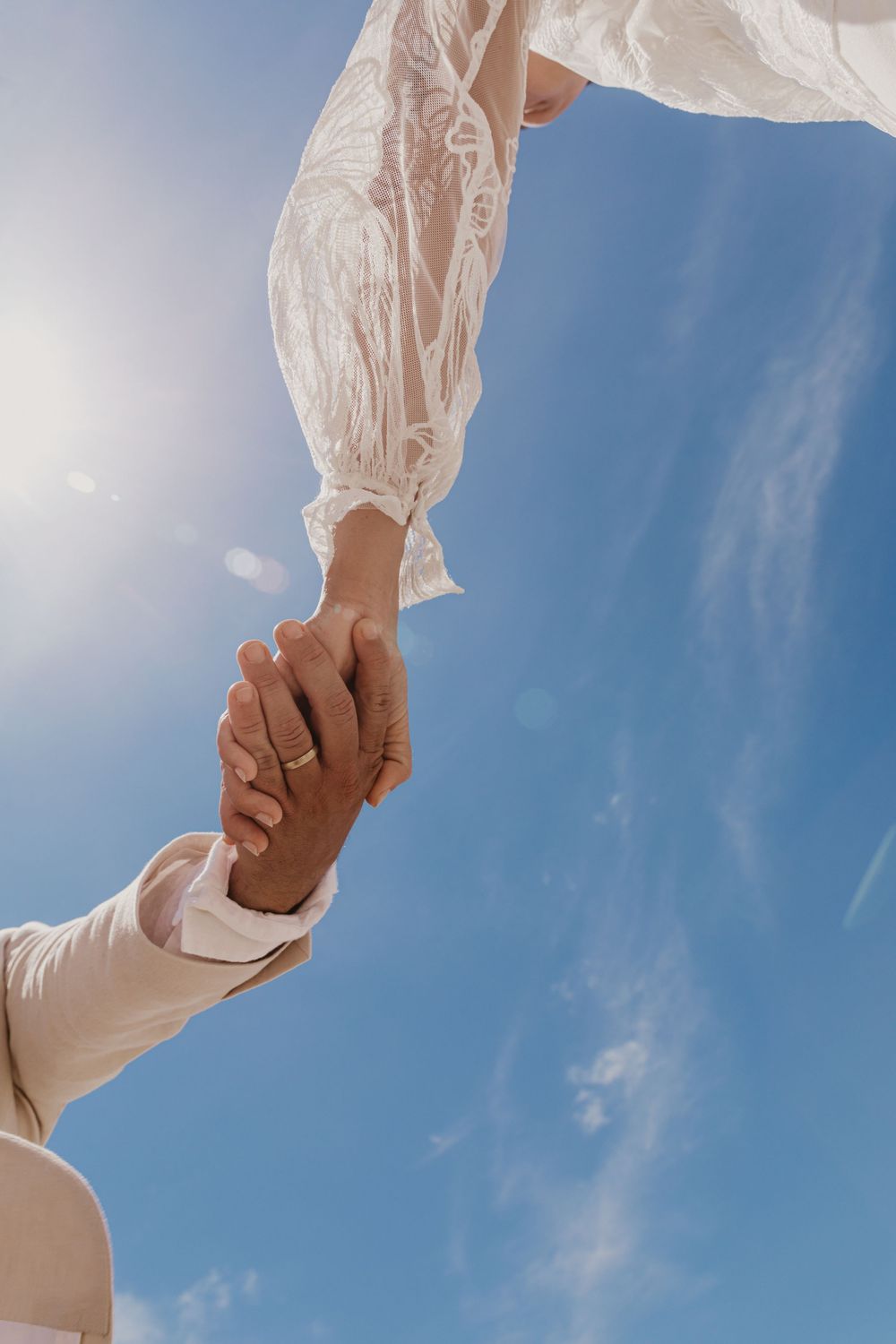 Bride and groom holding hands beneath the Byron Bay sky, celebrating their beach wedding with timeless, natural photography.