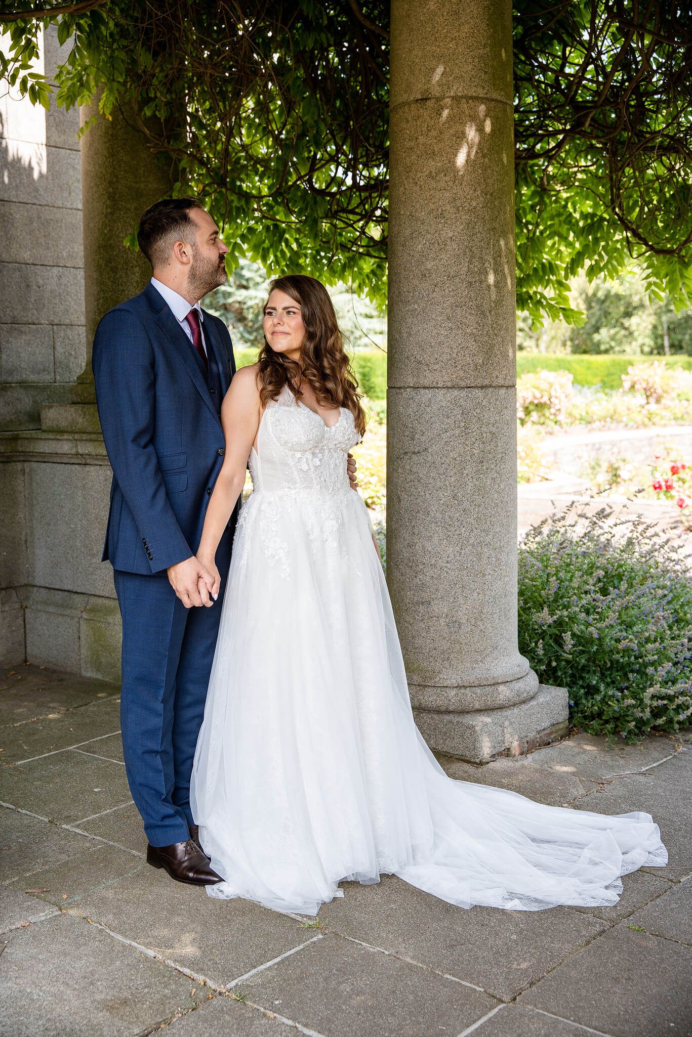 Bride in a white lace gown and groom in a navy suit at the memorial gardens county Dublin , Ireland.  photo by AK wedding photography.