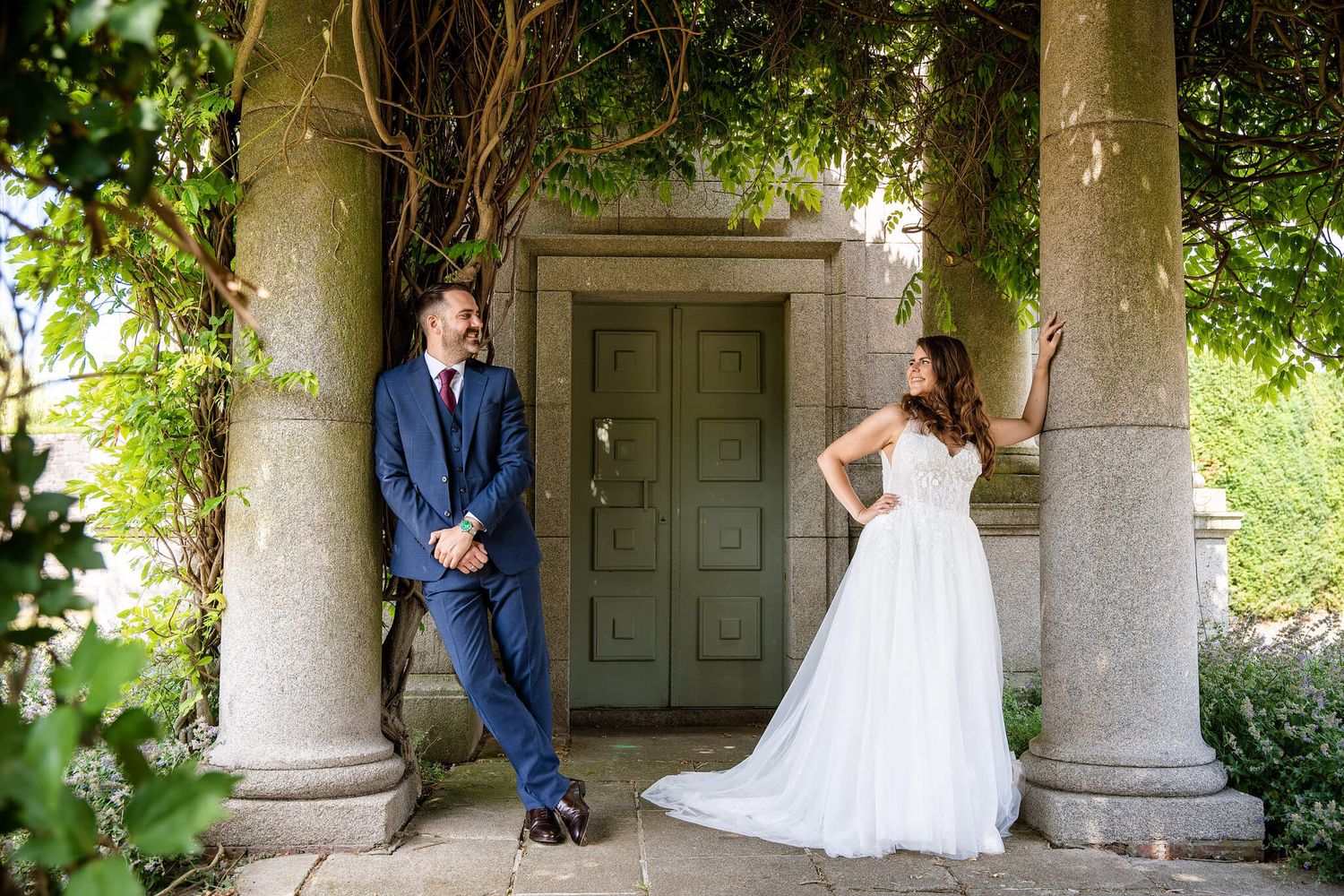 Bride in a white gown and groom in a navy suit pose at memorial gardens Dublin photo by AK wedding photography.