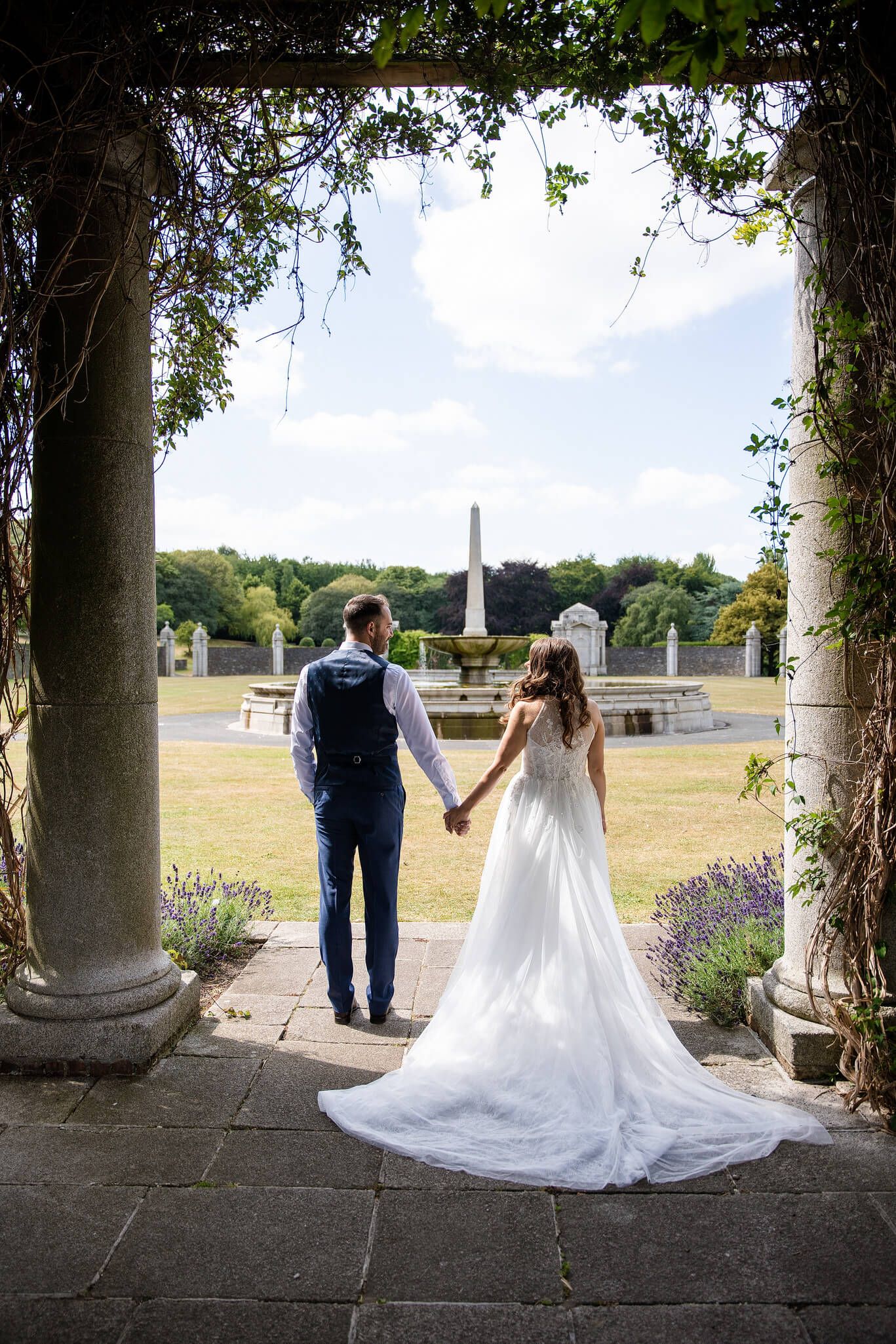 Bride in a flowing white gown and groom in a navy waistcoat at Irish war memorial photo by AK wedding photography.