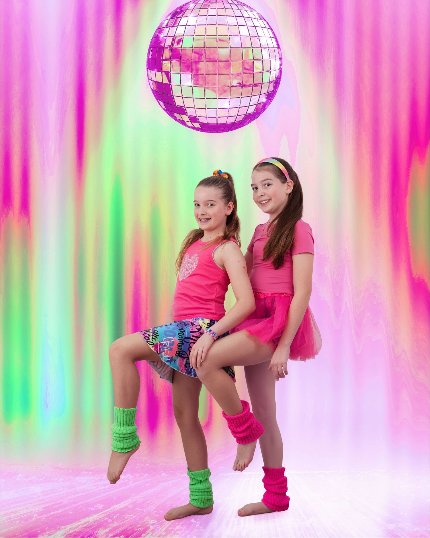 two young girls wearing neon 80's style clothes, posing with pink disco ball in an awkward style portrait