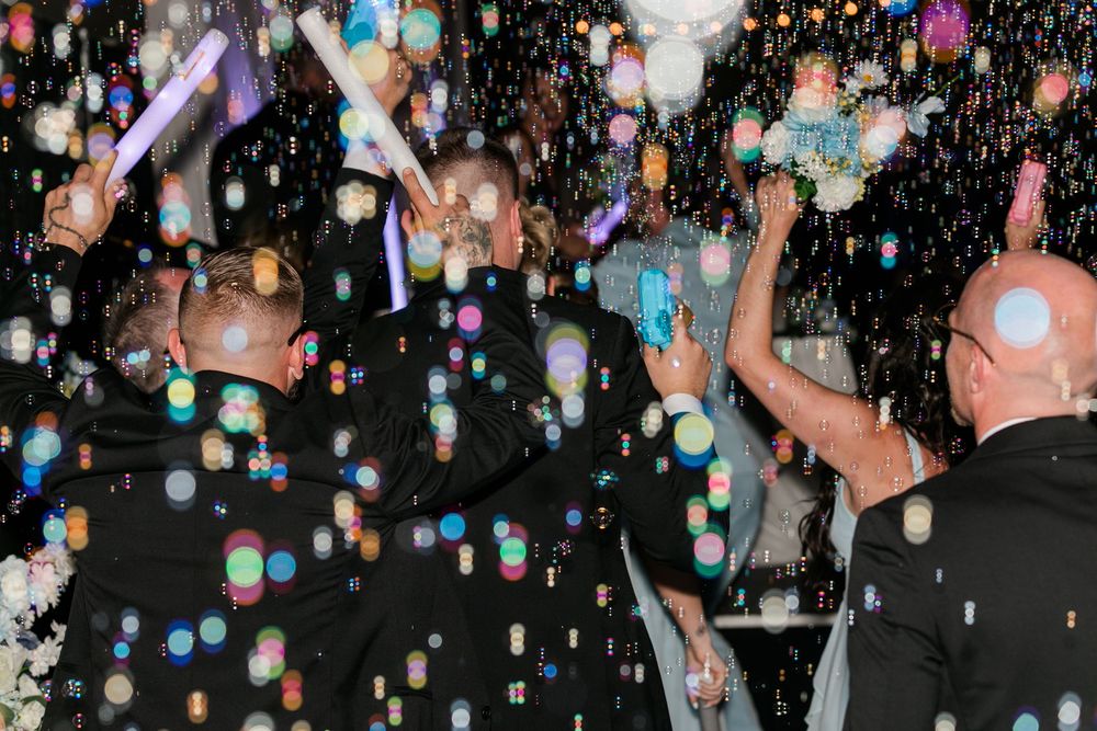 Joyful celebration with bubbles filling the air as guests dance at a festive evening party event.