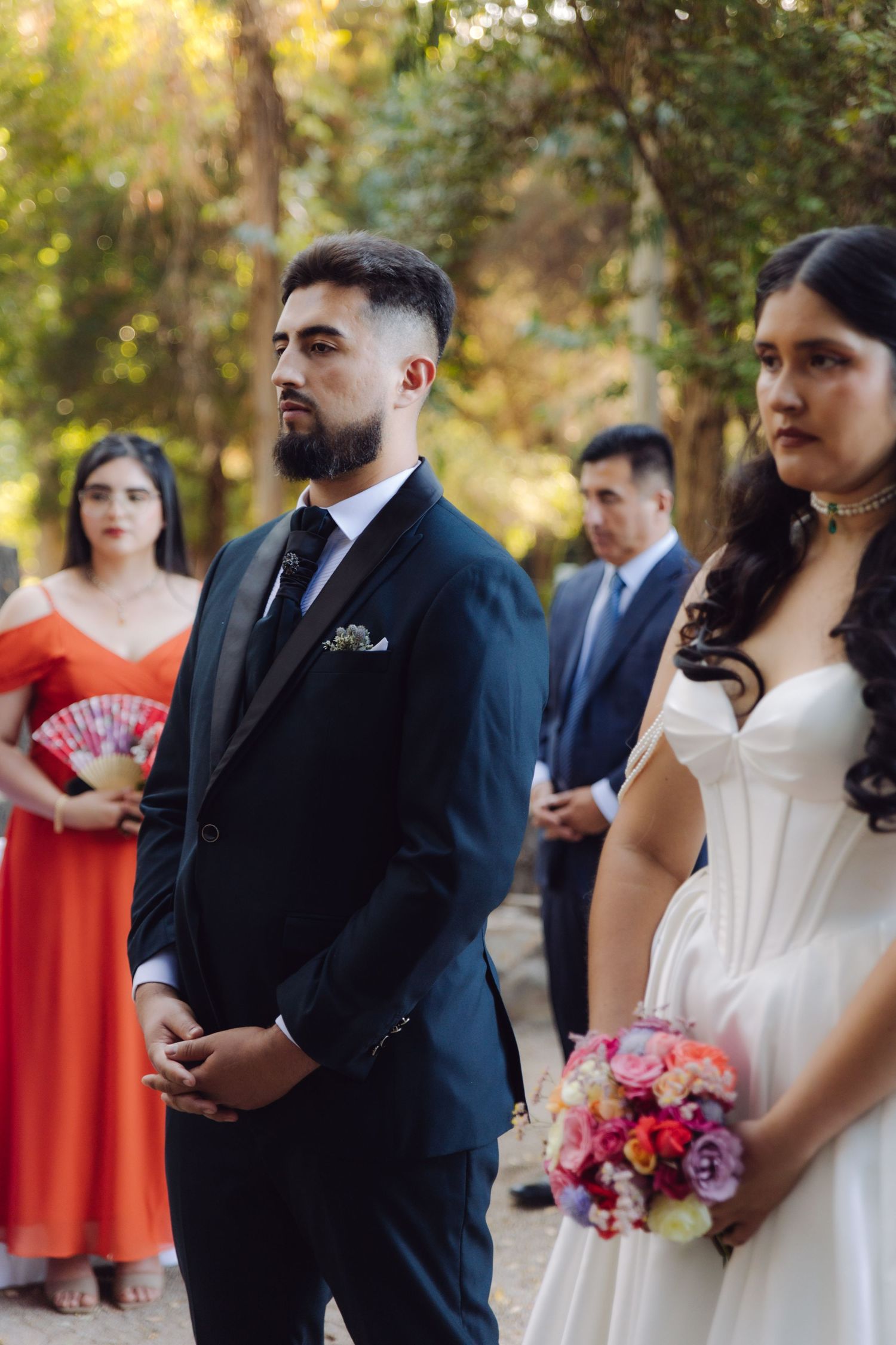 Groom in navy suit and bride in white gown stand at altar during outdoor wedding ceremony.