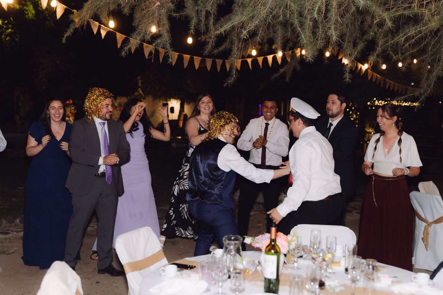 Guests dancing and celebrating together at a lively outdoor evening wedding reception.