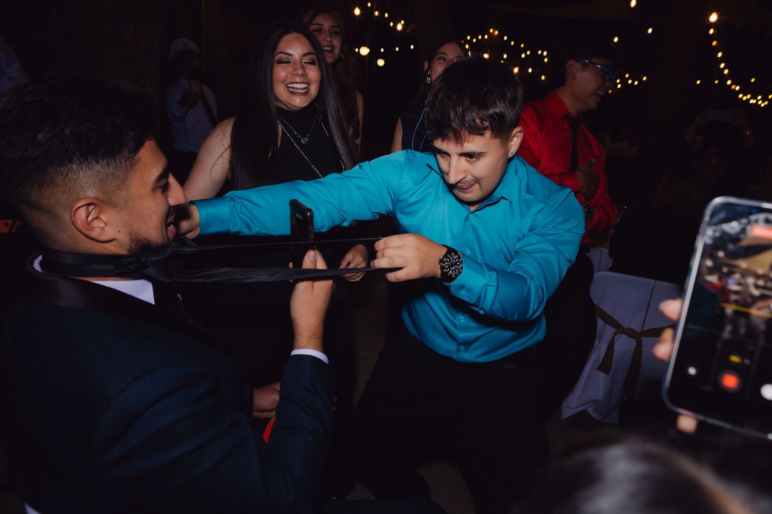Guests laughing and dancing together at a lively outdoor wedding reception.