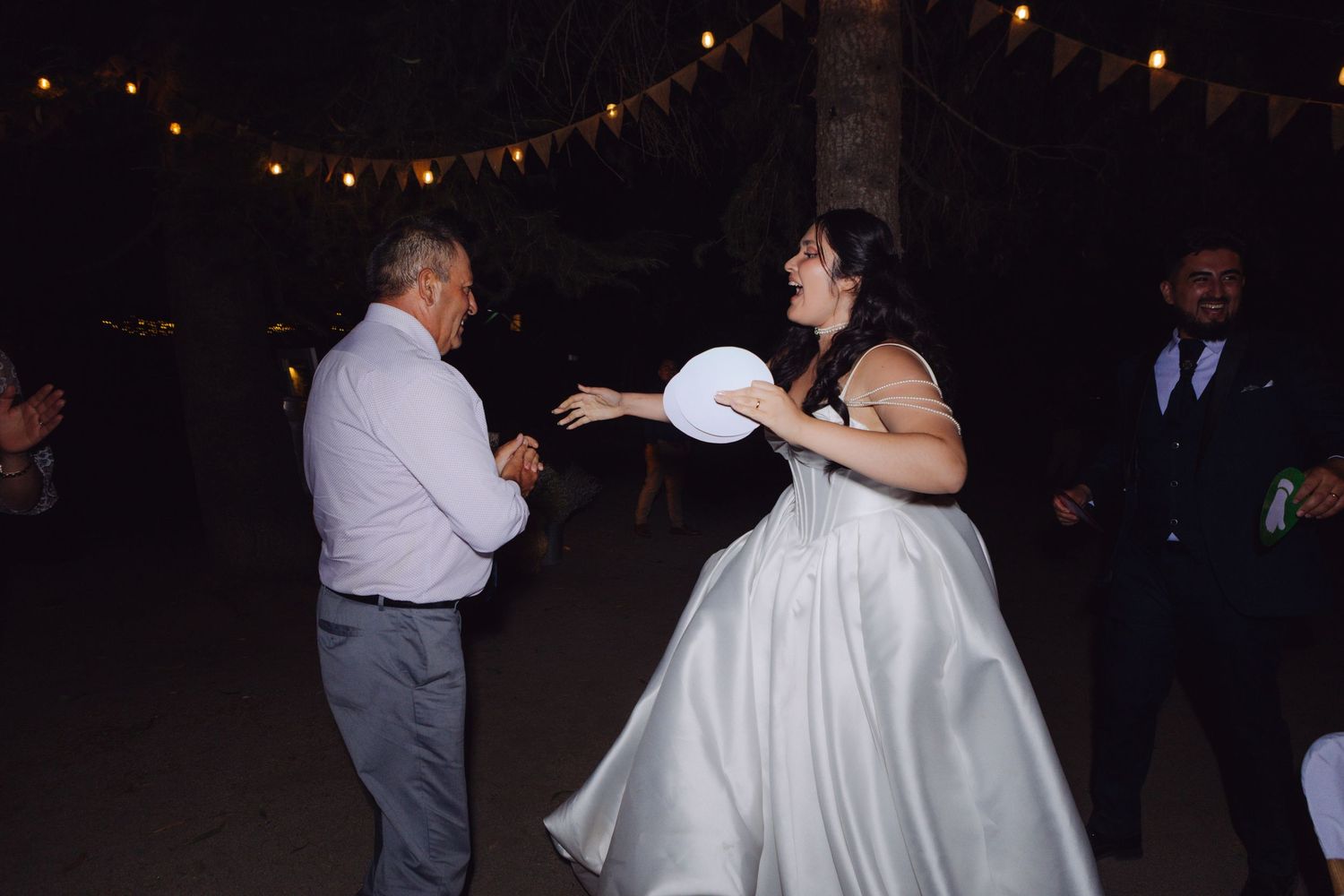 Bride in white ball gown playing with balloon with guest at reception.