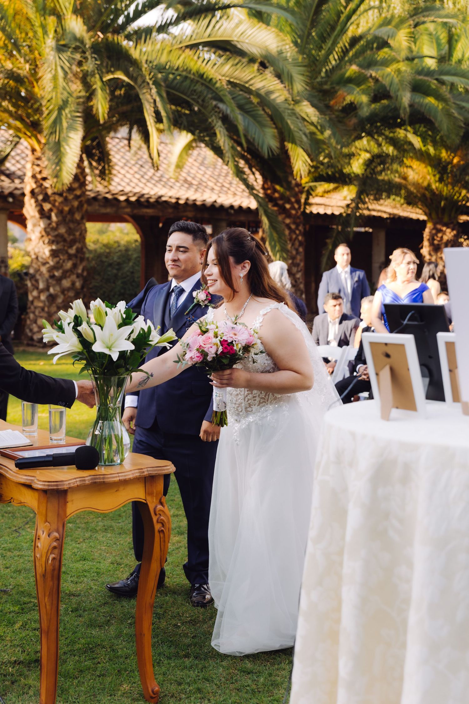 Bride and groom standing at altar during outdoor wedding ceremony near palm trees.