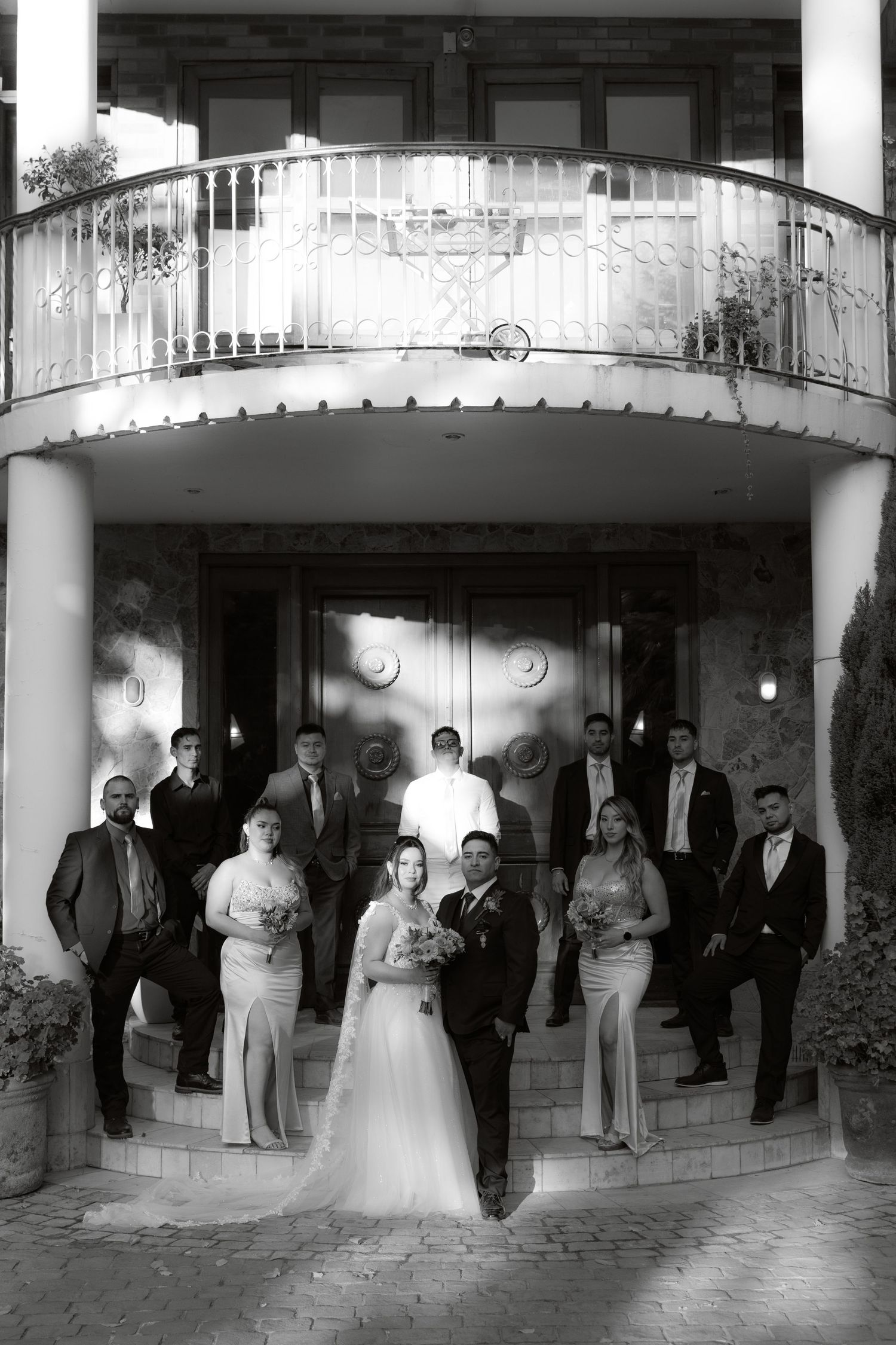 Black and white wedding party portrait posed on steps of an elegant building.