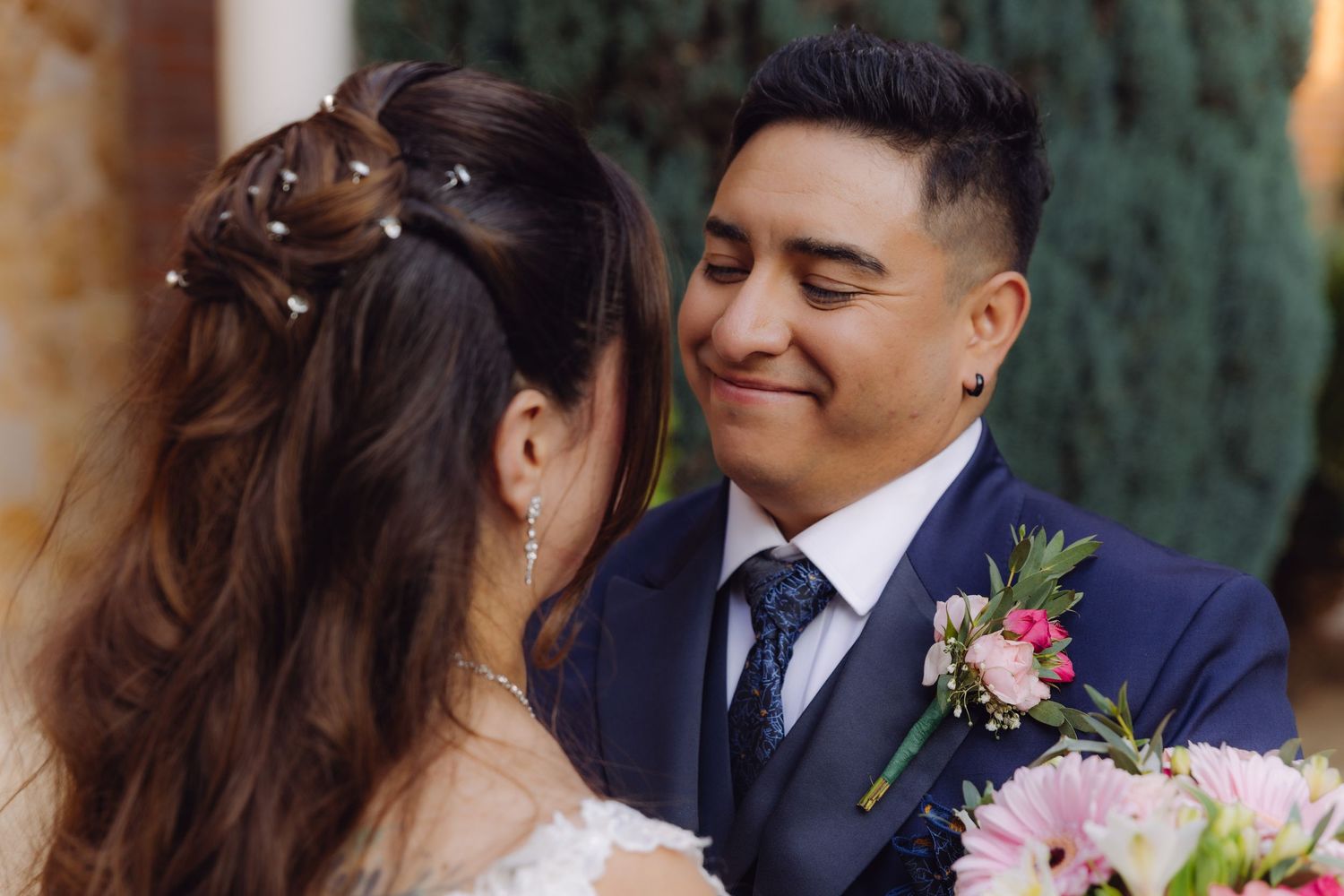 Groom smiling lovingly at bride during outdoor wedding portrait session.