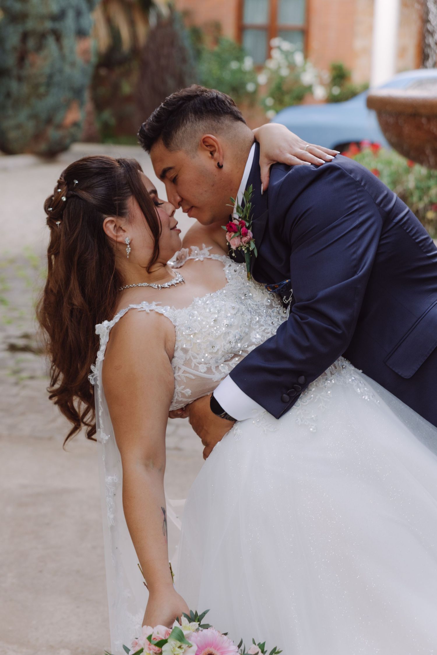 Groom dipping and kissing bride in a romantic outdoor wedding portrait.