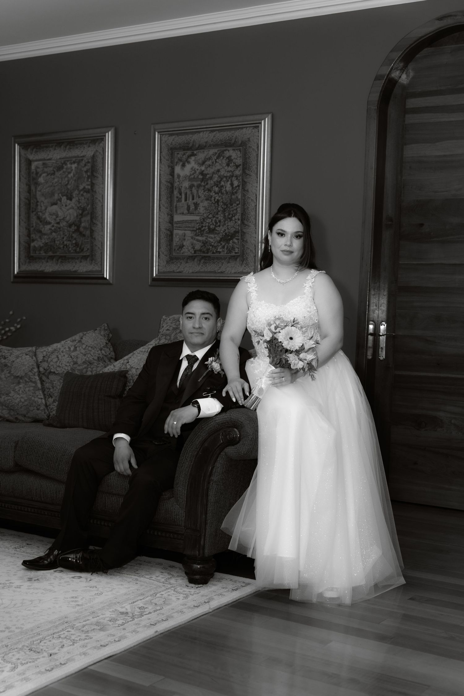 Black and white portrait of bride and groom posing elegantly in a decorated interior.