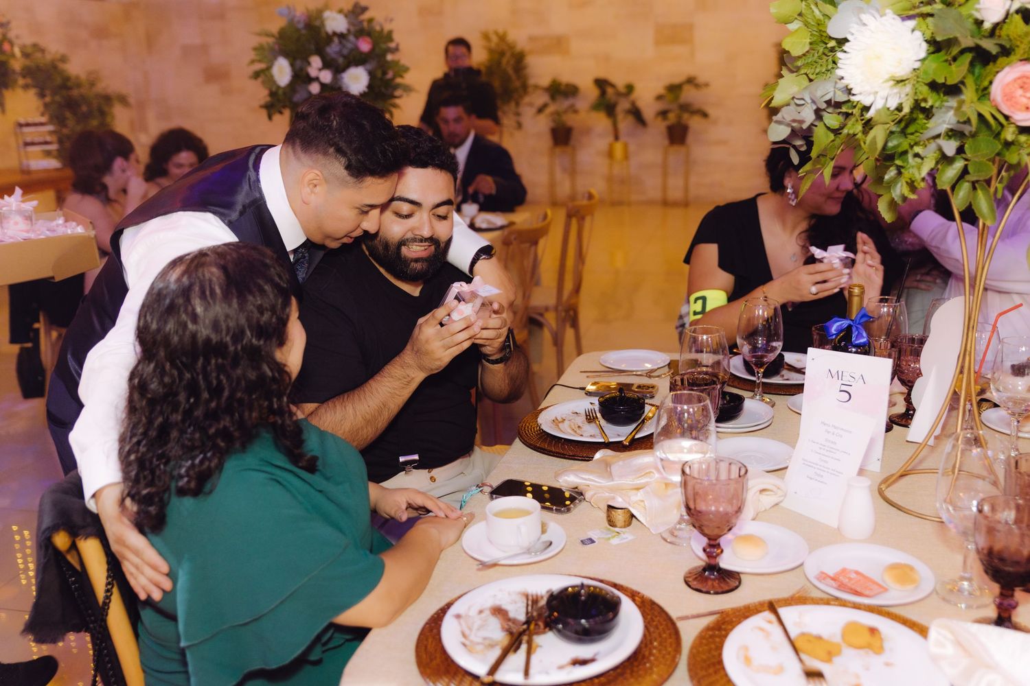 Wedding guests gathered around a table sharing a joyful moment during the reception dinner.