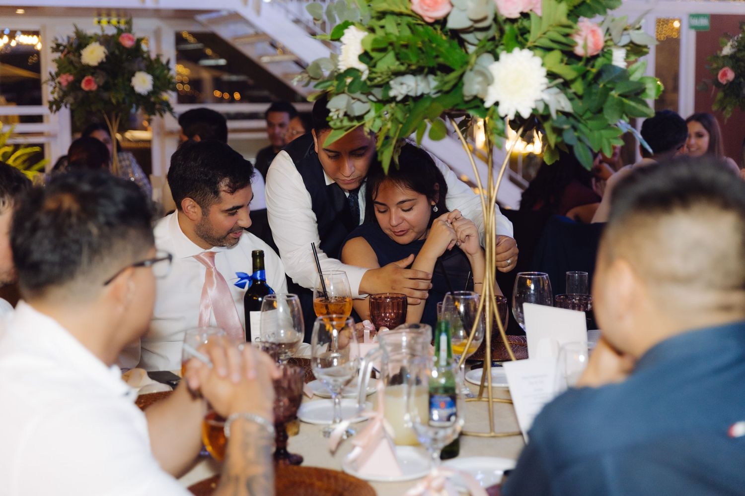 Wedding guests enjoying dinner at a beautifully decorated reception table with floral centerpieces.
