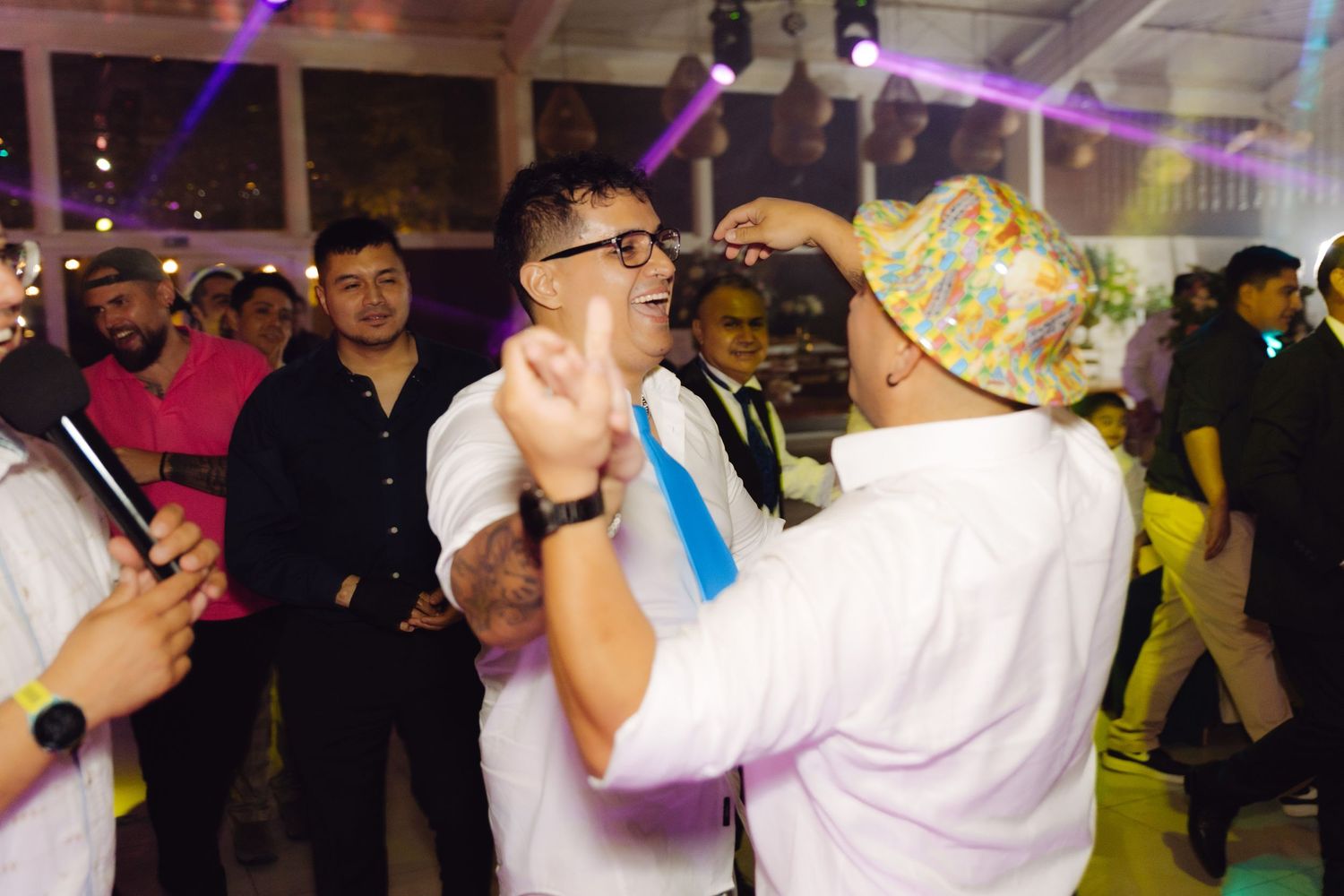 Two men dancing and celebrating energetically on the dance floor at a festive wedding reception.
