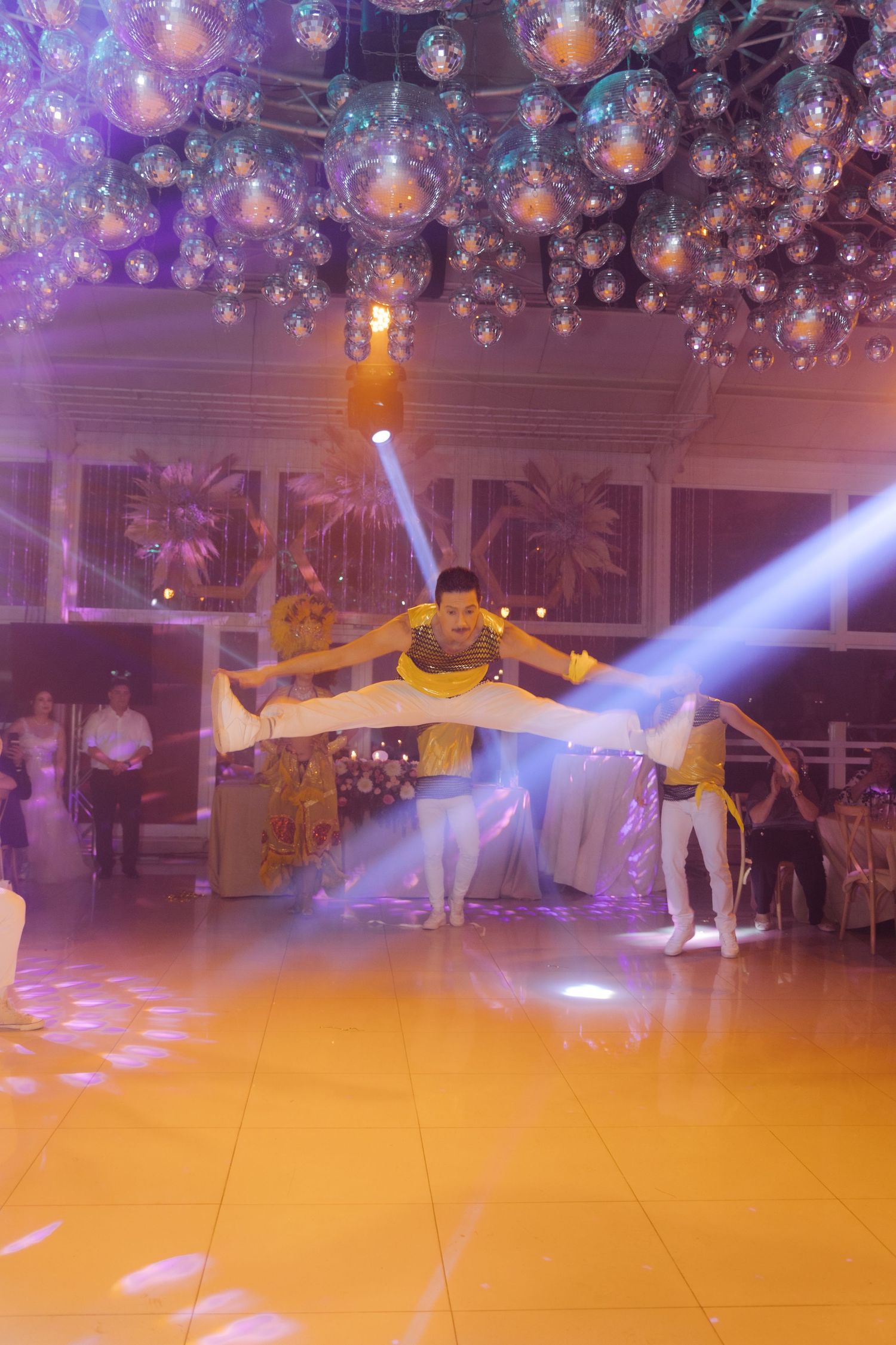 Acrobatic performers executing a stunning lift under a glittering disco ball ceiling at an elegant event.