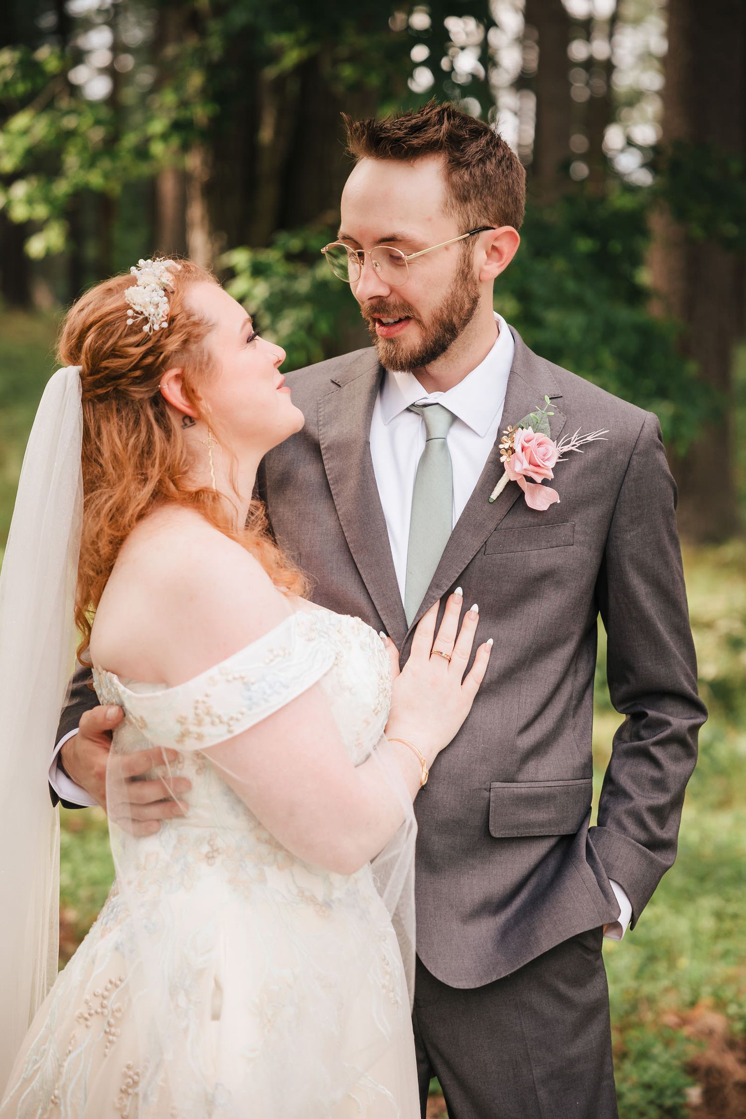 Groom speaking softly to the bride as she rests her hand on his chest, both smiling.