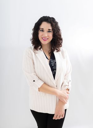 Professional woman in striped blazer smiling confidently against white background.