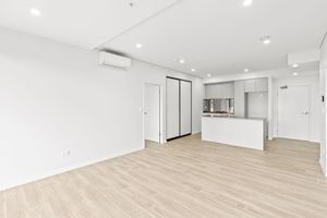 Spacious open-plan living area with white kitchen island and light timber floors.