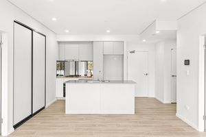 Modern white kitchen with island bench, mirrored splashback and light timber flooring.