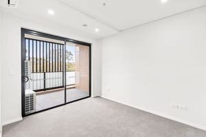 Carpeted bedroom with sliding glass door opening to balcony in modern apartment.