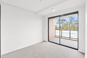 Empty bedroom with carpet flooring and sliding glass door leading to sunny balcony.