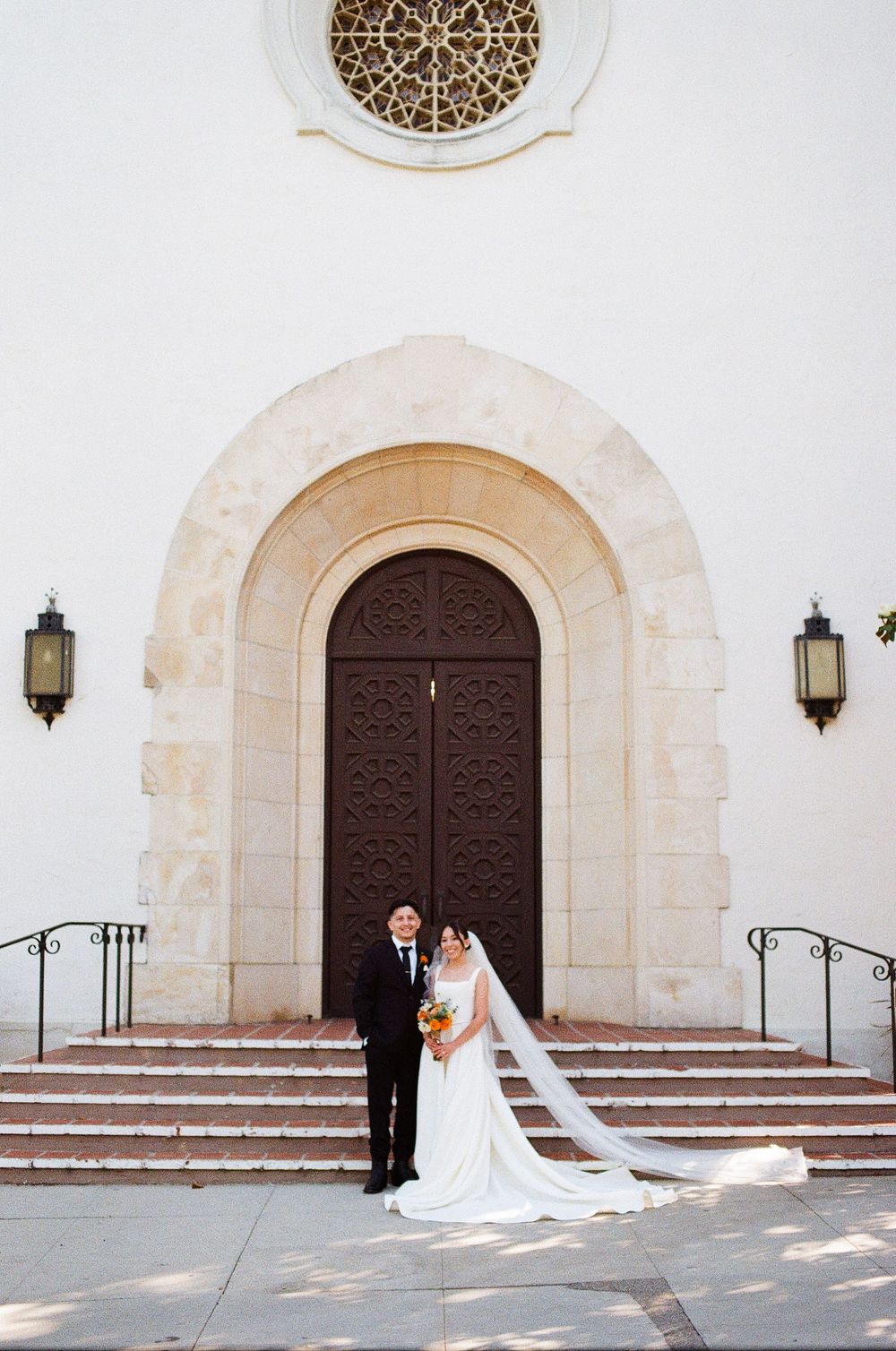 A couple at a classic California mission style building on their wedding day, photo taken on film medium.