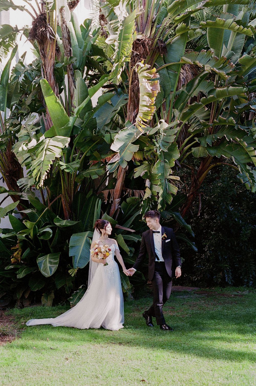 A couple walk hand in hand through gardens in Central California on their wedding day.