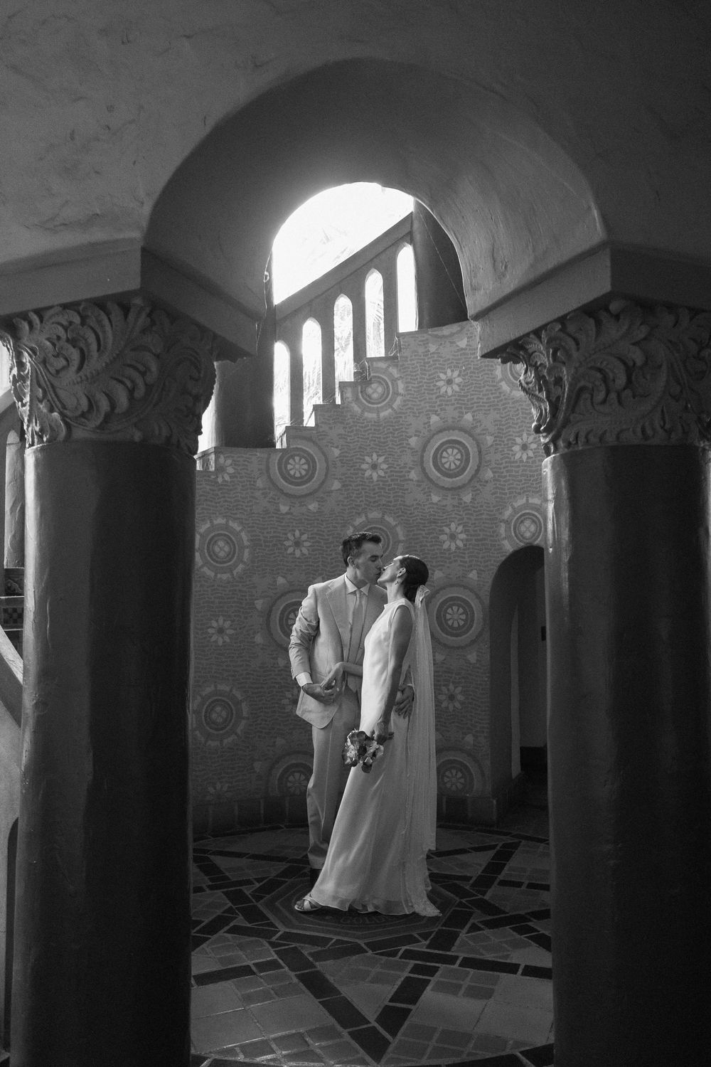 The iconic Santa Barbara Courthouse staircase shows a man and woman kissing in between the pillars.