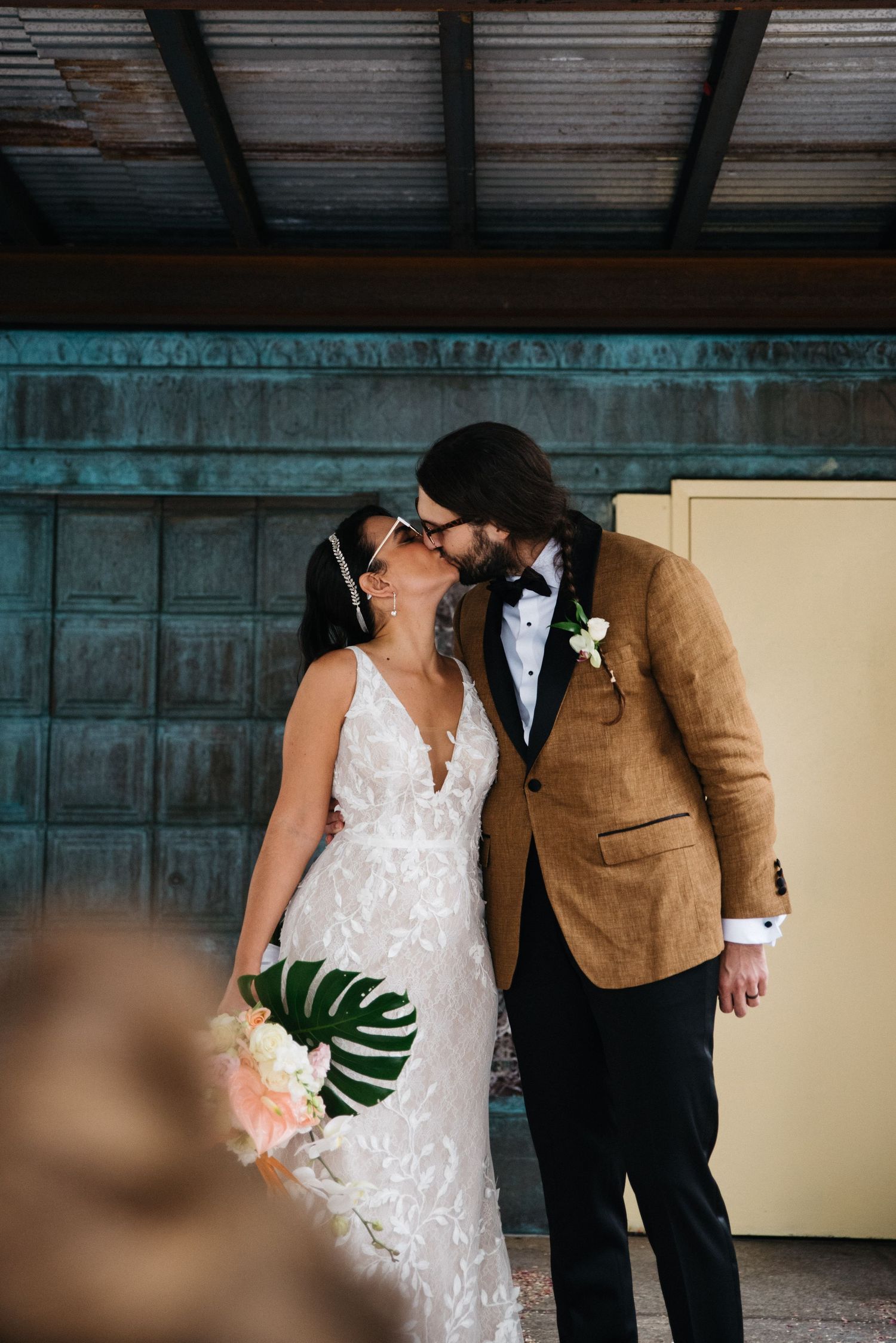 A tender wedding moment between a couple with a white lace dress and tan suit jacket.