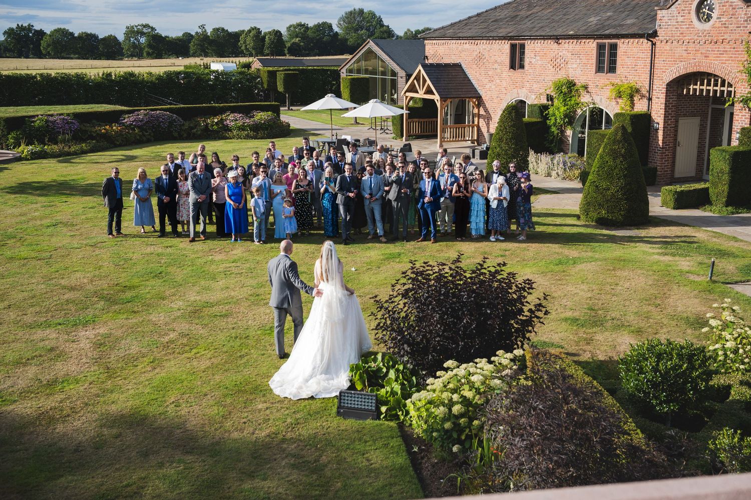 Charlotte and Niall with their people on the lawn at Merrydale Manor, Cheshire