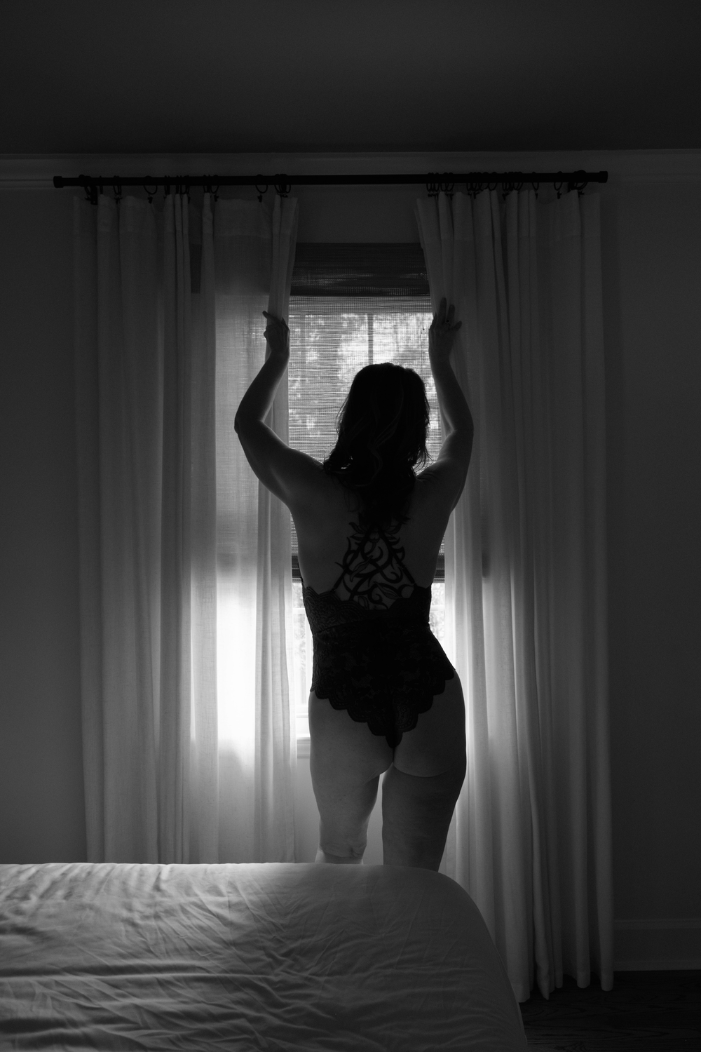 Luxury hotel suite in Raleigh featuring floor-to-ceiling windows and dramatic white curtains for portraiture.
