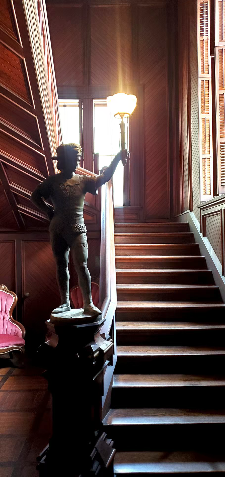 Bronze torch-bearing statue stands at base of ornate wooden staircase in the mac-o-chee wedding venue castle