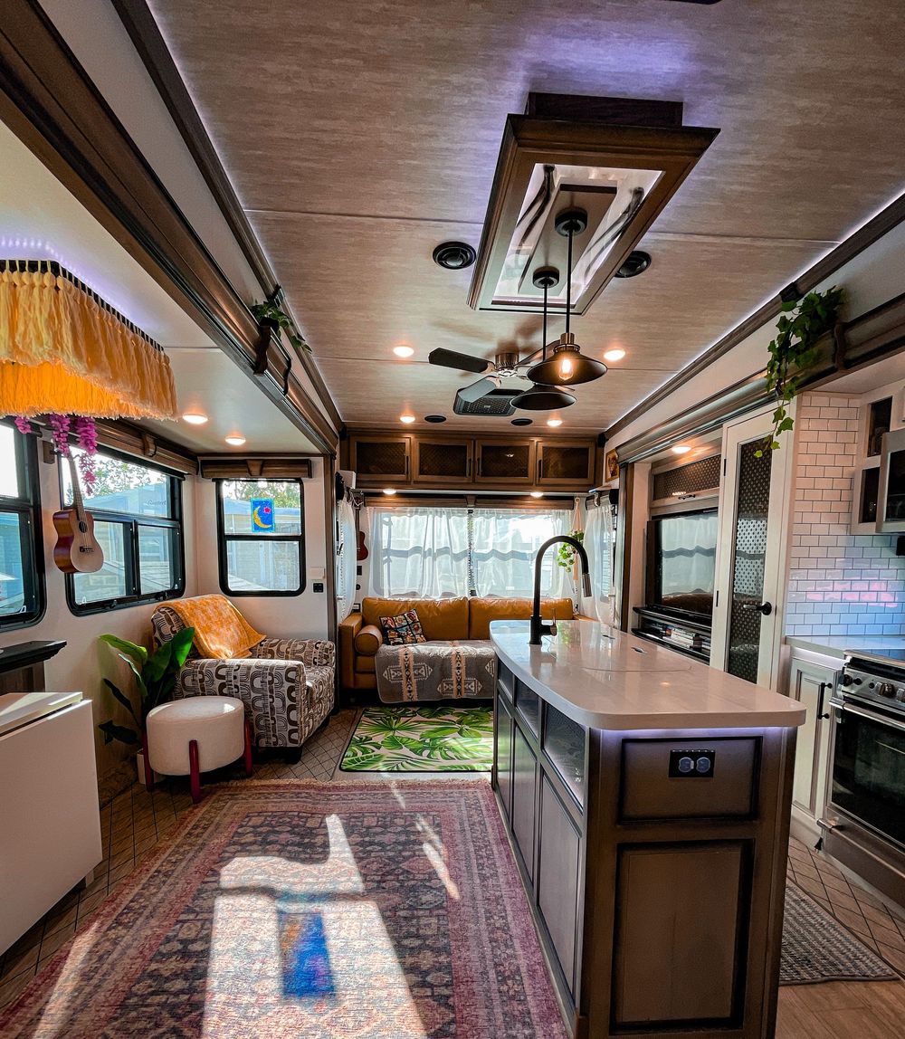 Stylish RV interior with bohemian decor, kitchen island, and Persian rugs.