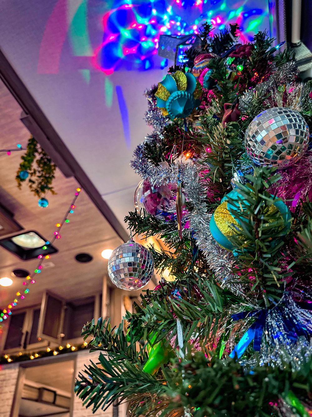 Festive RV Christmas tree decorated with disco ball ornaments, tinsel, and colorful twinkling holiday lights.