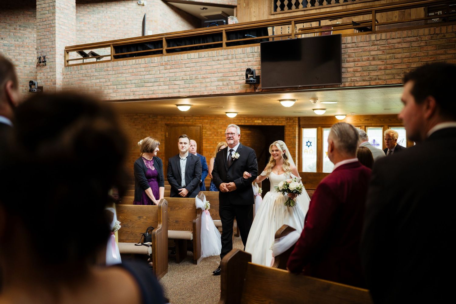 Bride and groom walking down the aisle during a church wedding ceremony with guests seated in wooden pews.