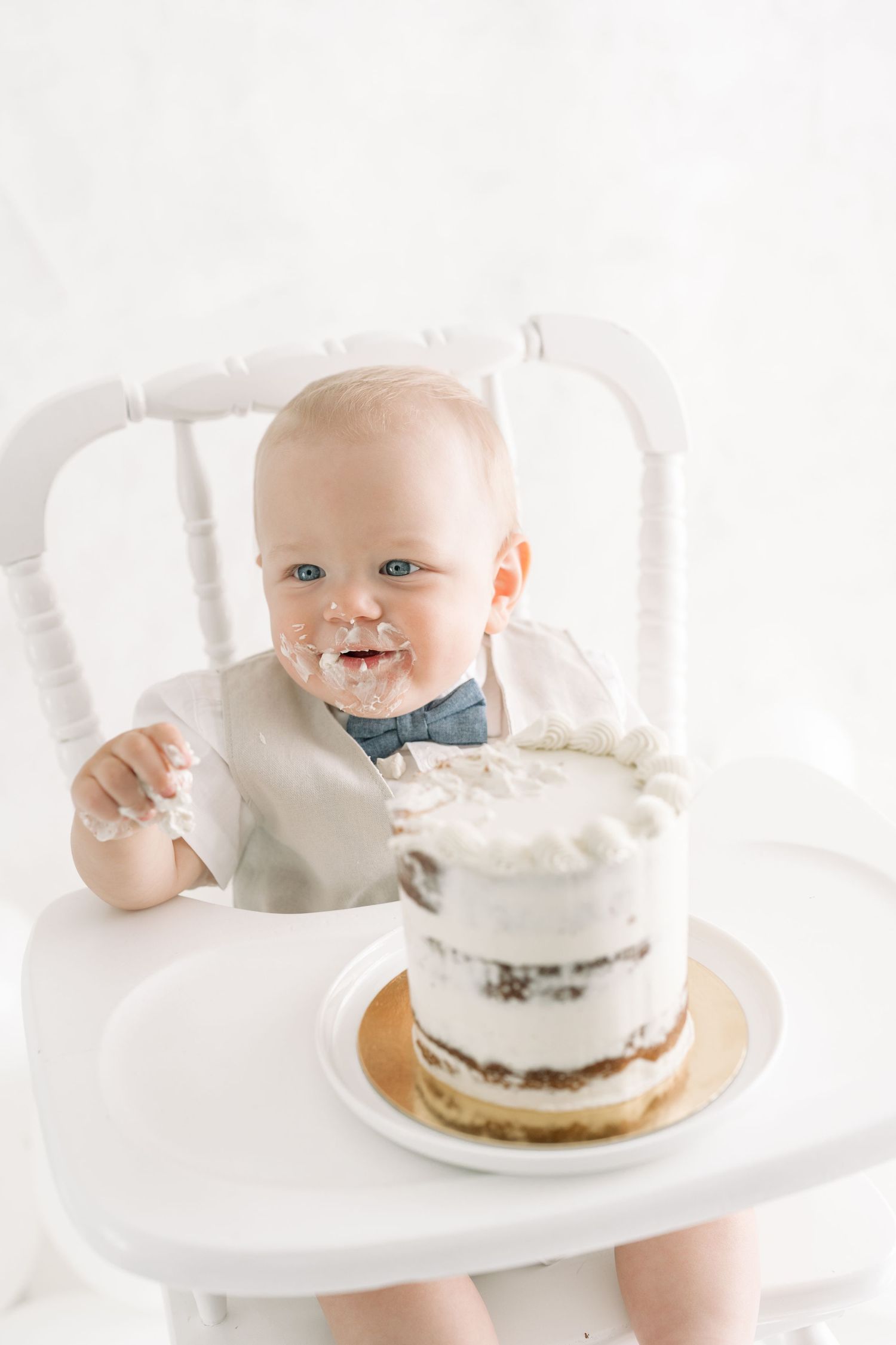 Bébé très content de son gâteau d'anniversaire, du crémage blanc sur ses joues et sa bouche