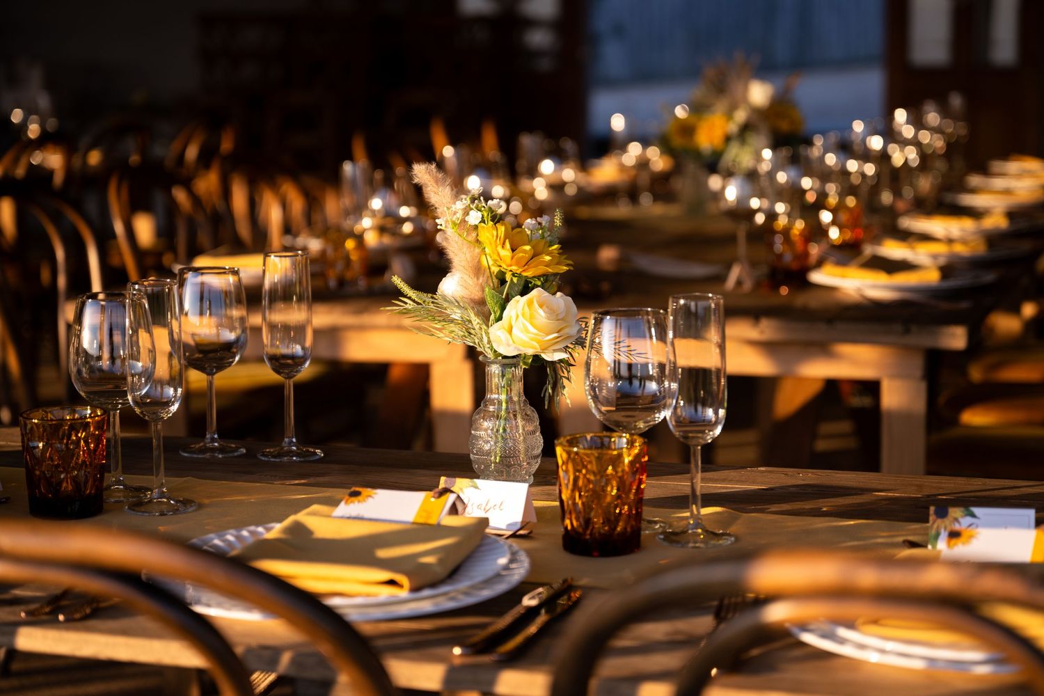 Elegant dinner table setting with wine glasses, floral centerpieces, and warm candlelight at a formal event.