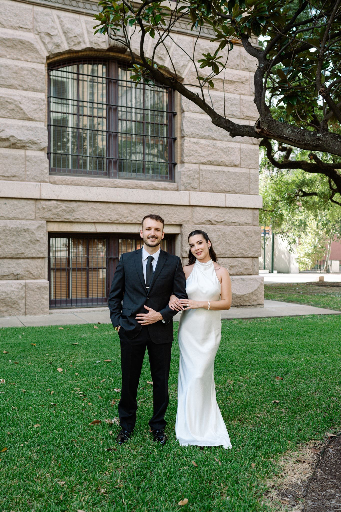 Bride and groom holding hands on the lawn of the historic 1910 Harris County Courthouse.