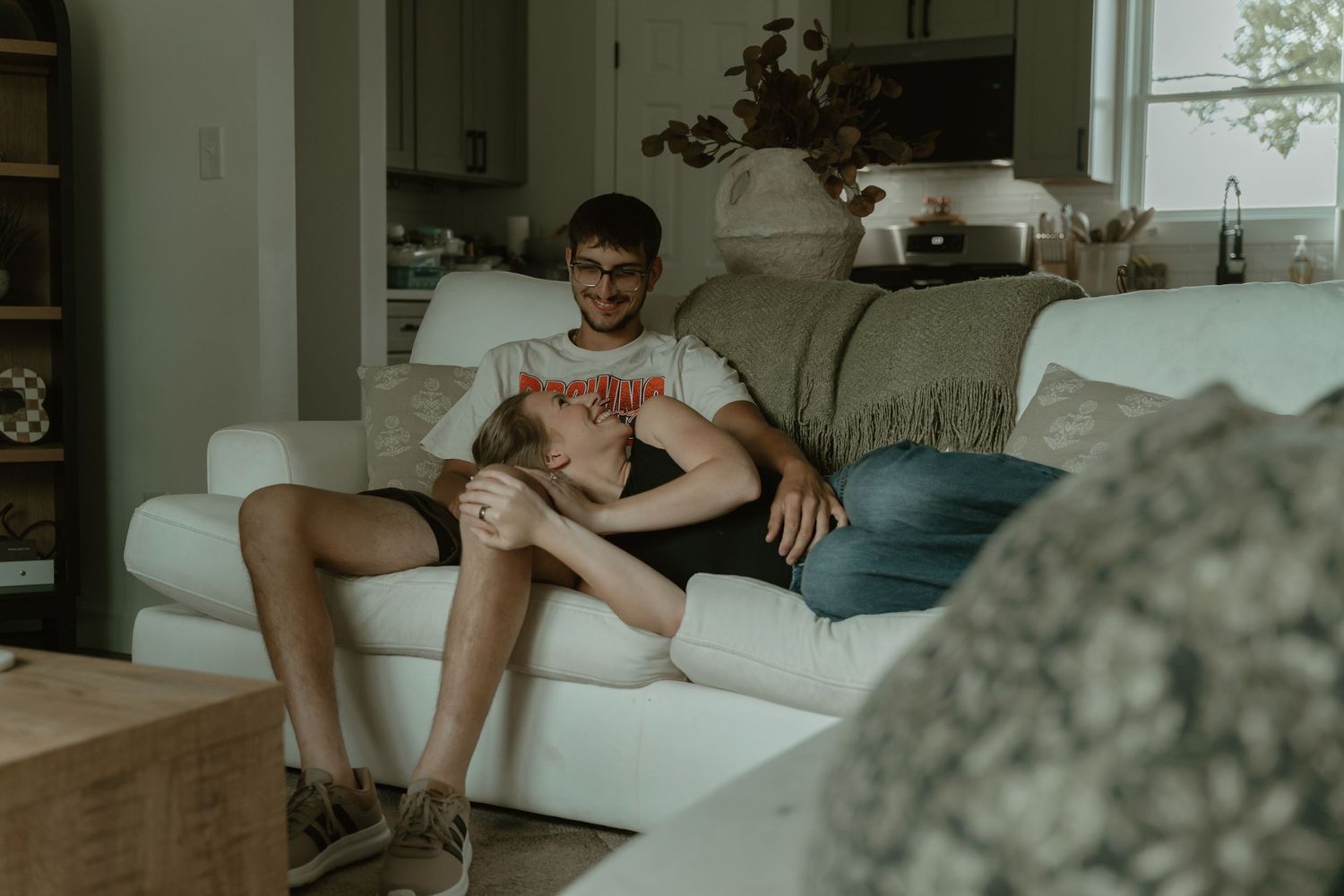 Couple relaxing together on a white couch in a cozy living room, sharing an intimate moment at home.