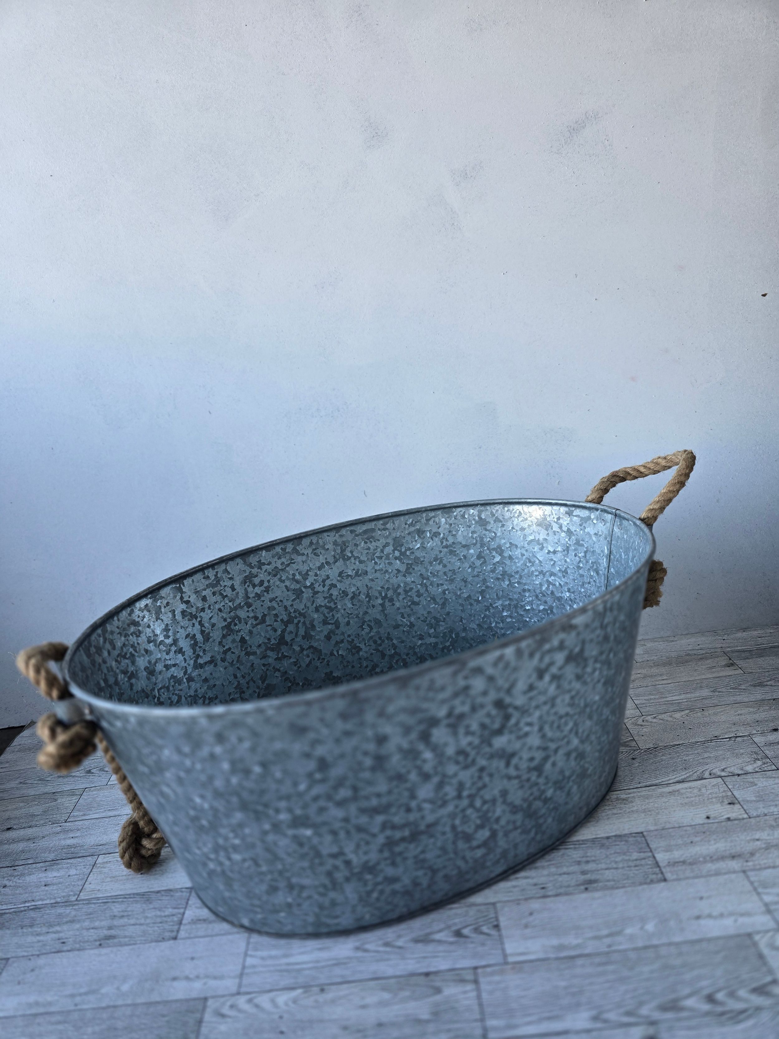 Oval galvanized metal tub with rustic rope handles, perfect for farmhouse decor, storage, or beverage cooling.