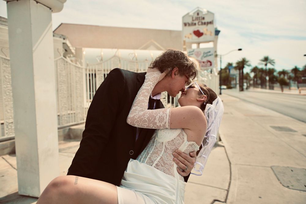 Newlywed couple sharing a romantic kiss outside the Little White Chapel wedding venue in Las Vegas.