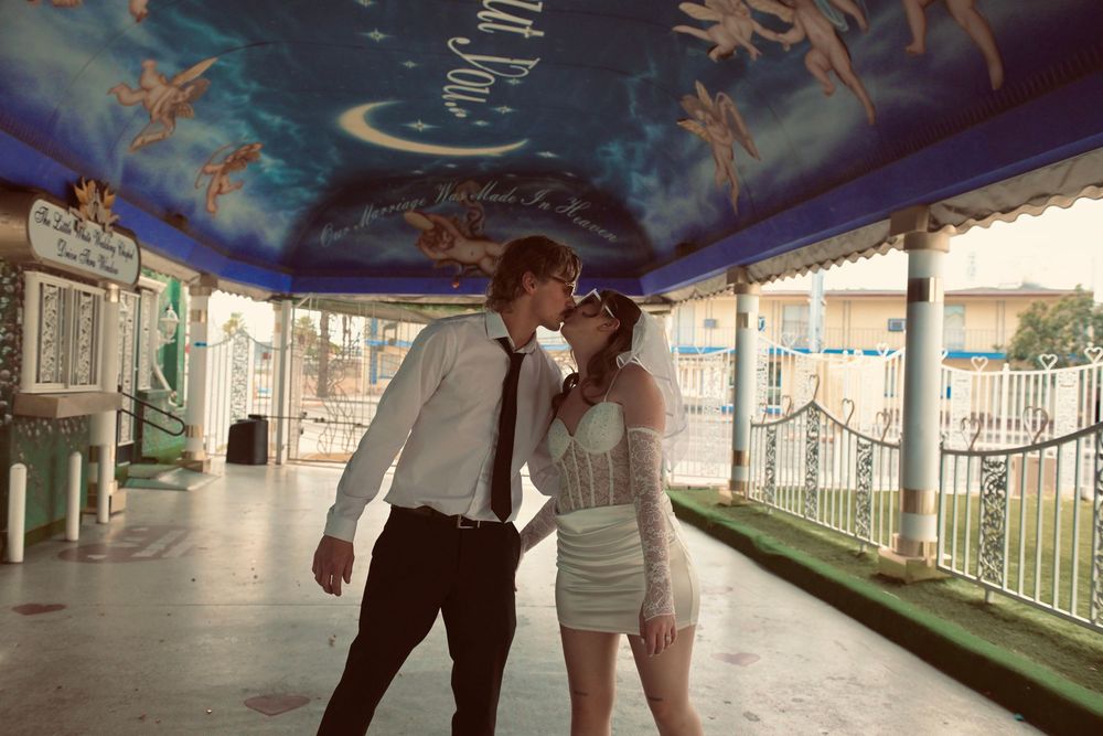 Couple sharing a romantic kiss under a painted celestial ceiling at a fairground pavilion.