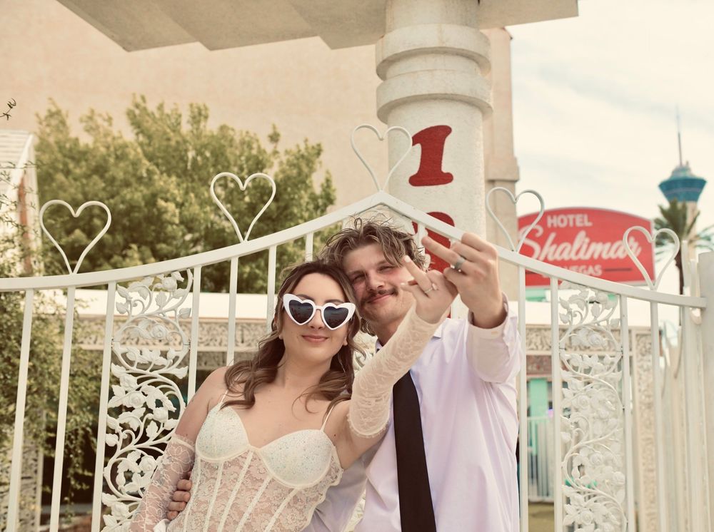 Bride and groom taking a selfie outside a Las Vegas wedding chapel with heart-shaped decorations.