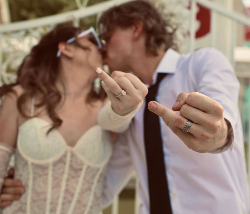 Newlyweds kissing while showing off their wedding rings at a Las Vegas chapel ceremony.