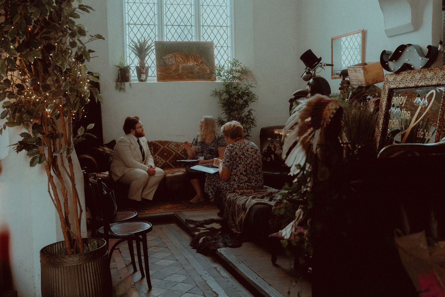 People gathered in a cozy, plant-filled room for an intimate meeting or counseling session indoors.