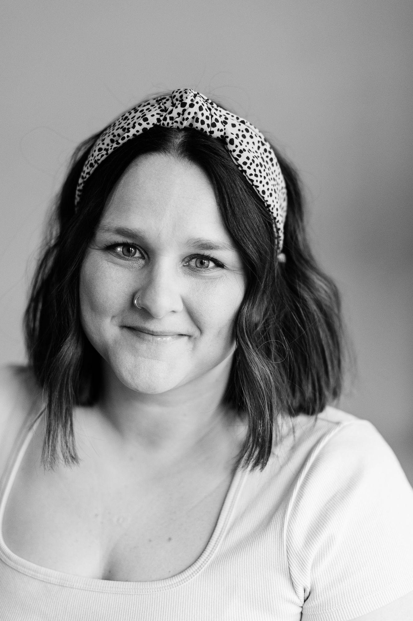 A portrait of a photographer wearing a patterned headband against a gray background.