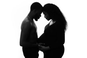 Silhouette of two people in an intimate pose with their foreheads touching against white background.